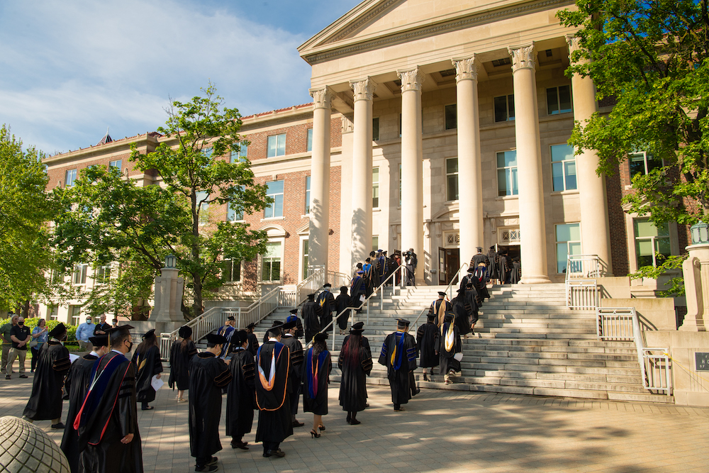 PhD graduates ascending the steps of Hovde Hall in full regalia