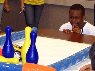 A camper knocks down bowling pins with the Lego Robot he created at camp. 
