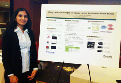 Aditi Gupta stands infront of her poster at PerCom 2011.