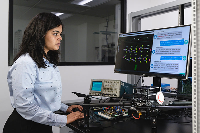 student works at standing desk with computer screens and electronic devices