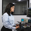 student works at standing desk with computer screens and electronic devices