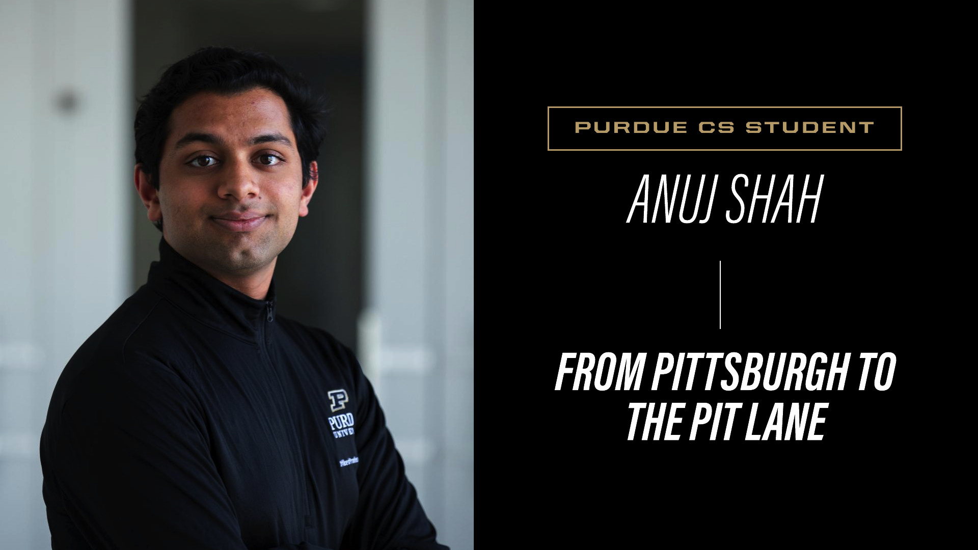 Anuj Shah in black Purdue quarter-zip jacket, arms crossed, smiling at camera against blurred indoor background.