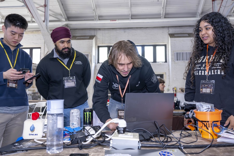 Balpreet Singh, (second from left), Ford Racing 3D Printing Engineer, watches as StarkHacks participants demonstrate their build. (Purdue University photo)