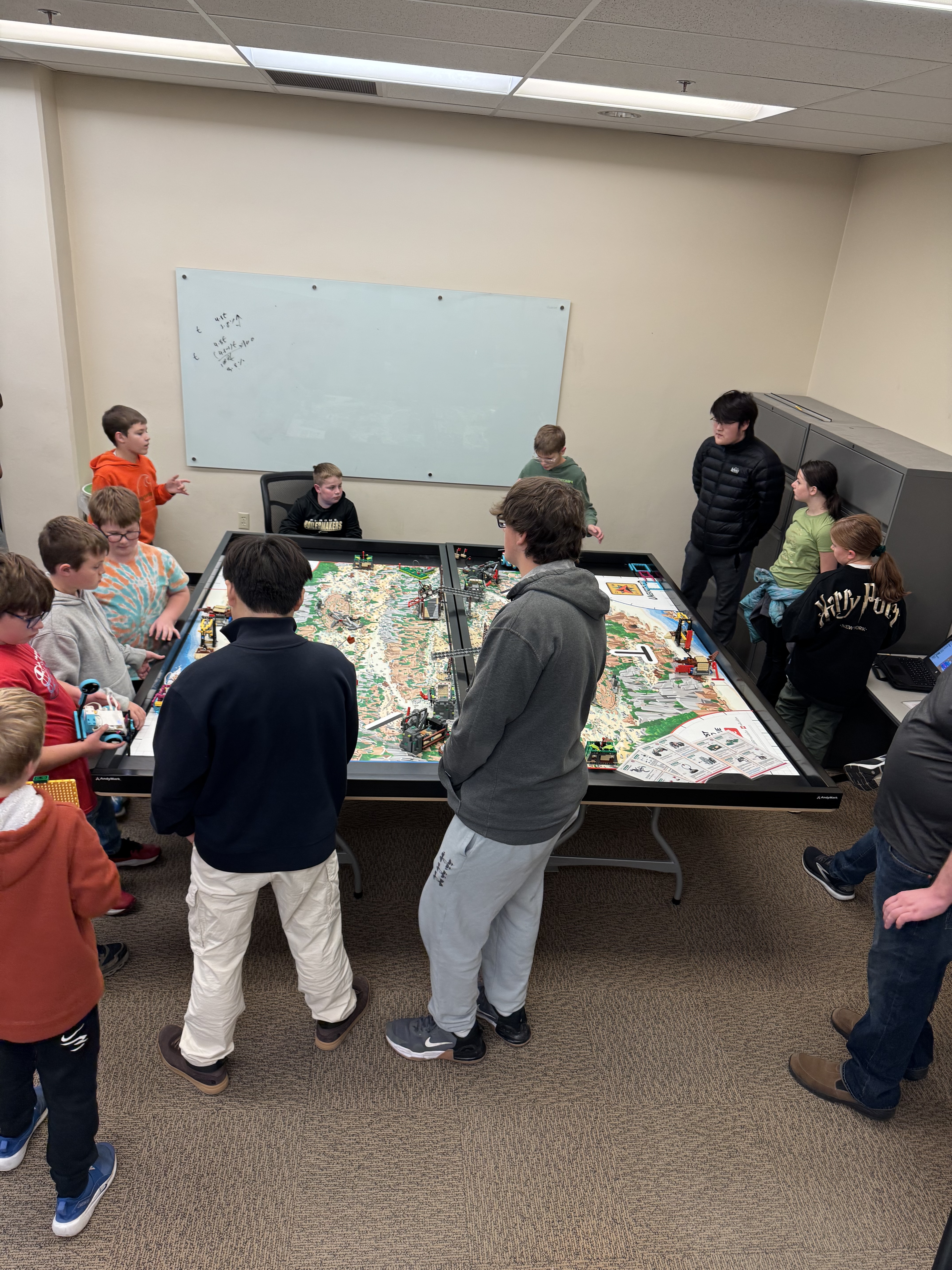 students discussing LEGO robots near playing field